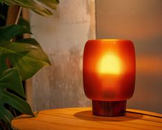 an orange light sitting on top of a wooden table next to a potted plant