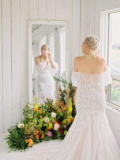 a woman in a wedding dress looking at herself in the mirror