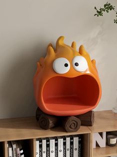 an orange and yellow toy sitting on top of a book shelf