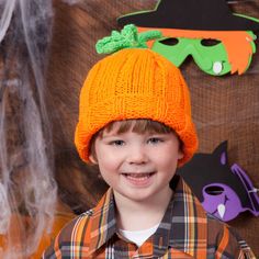 a young boy wearing an orange knitted pumpkin hat