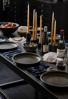 the table is set with plates, wine bottles and candles