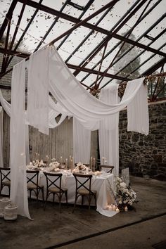 Minimalistic wedding tablescapes with ceiling drapes decoration and fairy lights Ivory Polyester Tablecloth Wedding, Drape Wedding Reception, Fabric Drapes Wedding, Candle Table Wedding Decor, Glass Room Wedding, Roof Draping Ideas, Curtains Wedding Decor, Fairy Lights On Ceiling Wedding, Wedding Roof Draping