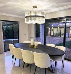 a dining room table with white chairs and a chandelier hanging from the ceiling