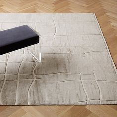 a black bench sitting on top of a wooden floor next to a white rug with lines drawn across it