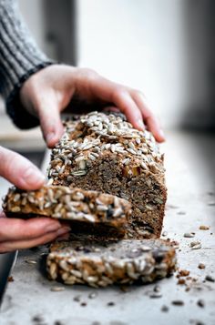 two hands are picking up some kind of bread