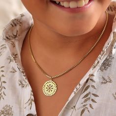 a close up of a person wearing a necklace with a medallion on it's neck