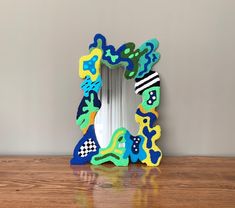 a colorful mirror sitting on top of a wooden table