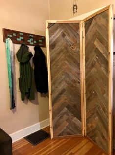 a room divider made out of wood with coat racks on the wall behind it