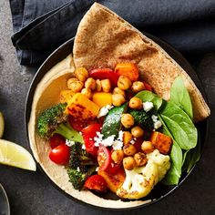 a bowl filled with vegetables and pita bread