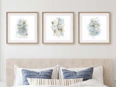 three framed pictures hang on the wall above a bed in a white bedroom with blue and beige decor