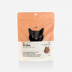 an orange bag with a black cat in it's pouch on top of a white surface