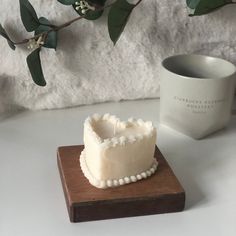 a small white cake sitting on top of a wooden board next to a coffee mug