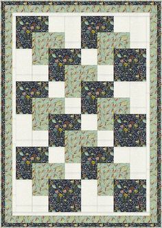 a green and white quilt with black squares on the center, in front of a blue background