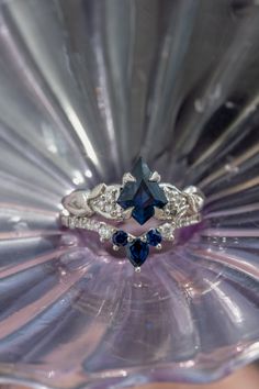 a blue diamond ring sitting on top of a glass vase