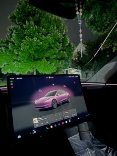 a laptop computer sitting in the middle of a car's dashboard, with an image of a pink sports car on it