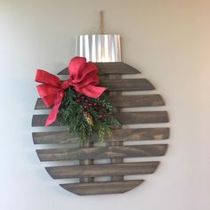 a wooden plaque with a red bow and pine cones on it, hanging from the wall