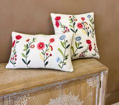 two pillows sitting on top of a wooden cabinet