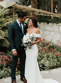 a man and woman standing next to each other in front of some flowers on the ground