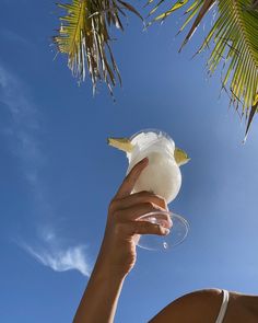 a woman is holding up a large piece of food in front of her face and palm trees