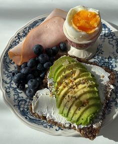 an open face sandwich with avocado, blueberries and eggs