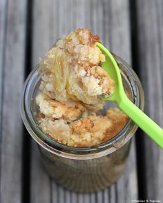 a spoon with some food in it on top of a glass jar filled with pudding