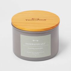 a candle with a wooden lid and label on the front that says, rainwater lily