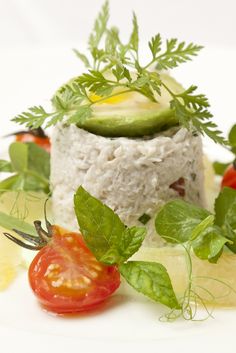 a white plate topped with rice and veggies next to sliced tomatoes, cucumbers and parsley