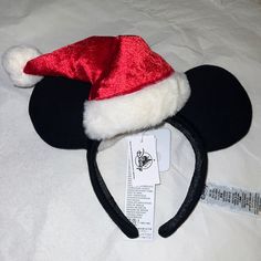 a red and white mickey mouse ear hat on top of a bed with a tag