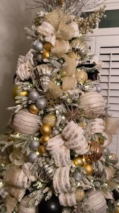 a decorated christmas tree with gold and silver ornaments