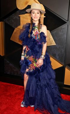 a woman in a blue dress and hat on the red carpet at an awards event