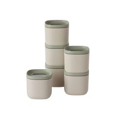 four white and grey containers stacked on top of each other, one with a green lid