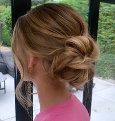 a woman with blonde hair is looking out the window and has her head in a bun