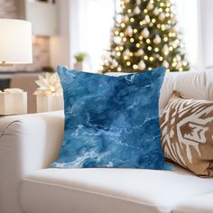 a blue pillow sitting on top of a white couch in front of a christmas tree