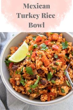 two bowls filled with rice and vegetables on top of a white table next to lime wedges