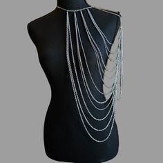 Introducing the majestic Silver Queen Body Chain, a stunning accessory that exudes elegance and strength. This remarkable body chain is meticulously designed to drape over the left shoulder, creating a captivating and empowering statement. Embrace your inner warrior queen and make a bold fashion statement with this extraordinary piece. The Silver Queen Body Chain features an intricate arrangement of looping chains of various sizes, symbolizing the unyielding spirit and resilience of a true queen. Its design reflects the perfect balance between elegance and strength, capturing the essence of a powerful and fearless leader. Crafted with meticulous attention to detail, the Silver Queen Body Chain is a testament to the craftsmanship and quality that goes into each piece. It is made from high-q Full Body Jewellery, Bohemian Body Jewelry With Chain Strap, Silver Adjustable Body Chain For Festivals, Silver Clavicle Chain Body Jewelry For Festival, Silver Clavicle Chain Body Chain For Festival, Silver Clavicle Body Chain For Festivals, Silver Body Jewelry With Clavicle Chain For Festival, Silver Body Chain With Clavicle Detail For Festival, Elegant Clavicle Chain Body Jewelry For Festivals