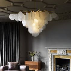 a living room filled with furniture and a large light fixture hanging from the ceiling over a fire place