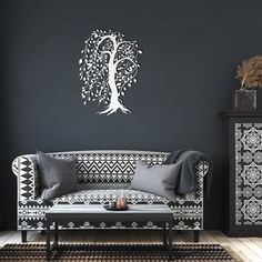 a black and white living room with a tree wall decal on the wall next to a couch