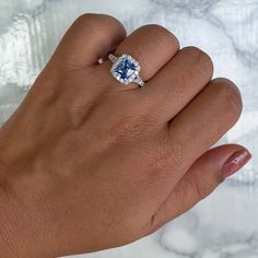 a woman's hand with a blue and white diamond ring on her left hand