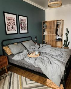 an unmade bed in a bedroom with two pictures on the wall and a basket