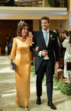 a man and woman in formal wear walking down the aisle at a wedding ceremony together