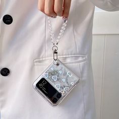 a person wearing a white coat and holding a cell phone in their pocket with a chain attached to it