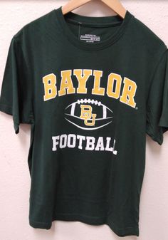 a t - shirt that says baylor football hanging on a hanger next to a wall