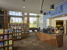 a woman is sitting at the check out counter in a library with bookshelves