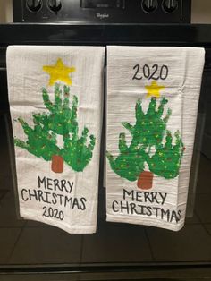 two white towels with christmas trees on them are hanging from the oven in front of an oven