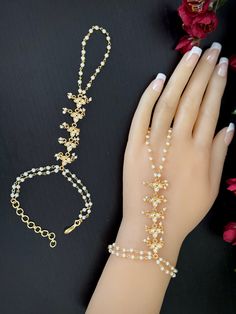 This is an Adjustable elegant pair of gold finished Moissanite pearl  phool /  hath  panja / hath paan / bridal bracelet / Finger ring Bracelet combo .  This modern hath Phool is a light weight version of the traditional Hand piece with a single ring. The length of the bracelet and the connection to Ring is given in one of the Pictures. Please take a look. Let us know if you have any questions on the item before ordering so you can shop confidently. Thanks Adjustable Metal Body Jewelry For Wedding, Hand Set Toe Ring Jewelry For Parties, Dainty Gold Beads Jewelry For Party, Dainty Gold Bead Jewelry For Party, Delicate Gold Body Jewelry For Party, Elegant Jeweled Body Jewelry For Gifts, Delicate Adjustable Gold Body Jewelry, Gold Body Jewelry With Pearl Chain As Gift, Gold Body Jewelry With Pearl Chain For Gift