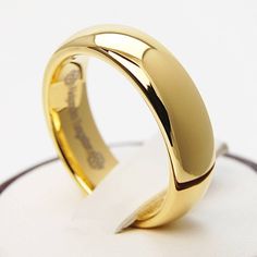 a gold wedding ring on top of a white surface