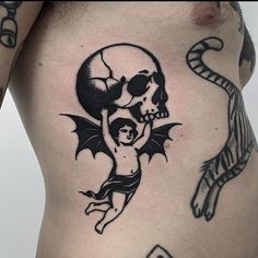 a man with a skull and bat tattoo on his stomach is holding a child in the air