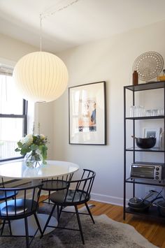 a dining room table with chairs and a vase on top of it in front of a window