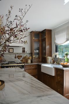 a kitchen with marble counter tops and wooden cabinets, along with a vase filled with flowers