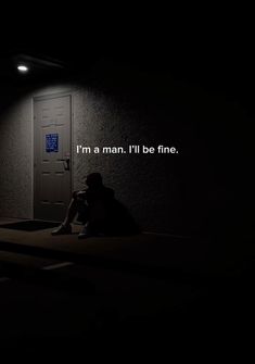 a person sitting on the floor in front of a door at night with an illuminated sign reading i'm a man, i'll'll be fine